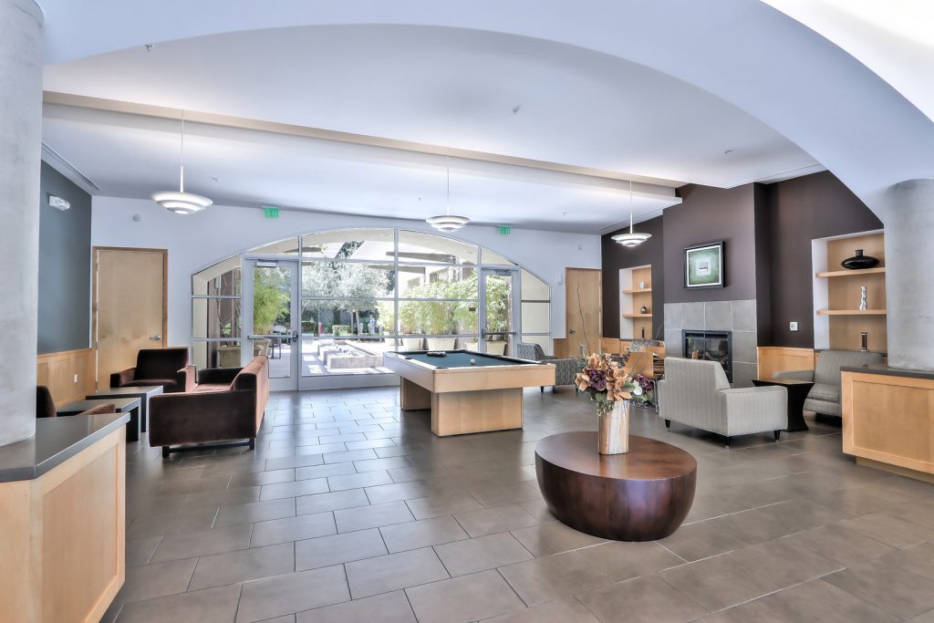 Resident lounge with pool table, fireplace, and seating area at Fruitdale Station apartments in San Jose
