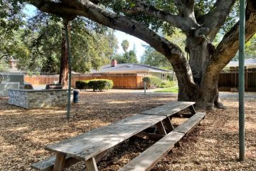 Outdoor barbeque area with wooden picnic tables.