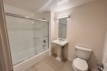Bathroom with bathtub/shower combo, sink, toilet, & tile floor.