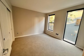 Bedroom with closet, windows, & carpet flooring.