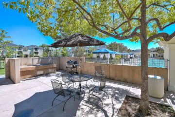 Outdoor barbeque area with seating and a tree.