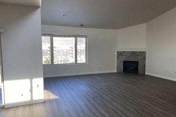 Open floor living room area with fireplace & large window.