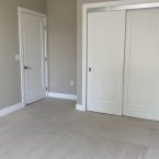 Bedroom with white doors and carpeting.