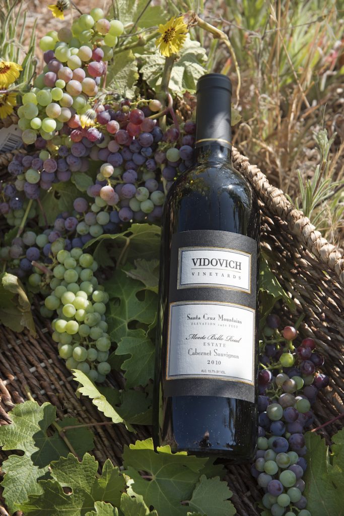Vidovich Vineyards Wine Bottle in a Basket with Grapes