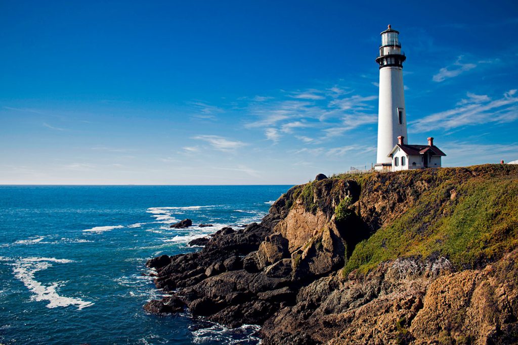 The Pigeon Point Lighthouse stands next to the ocean to guide ships along the Pacific coast in Pescadero, CA.